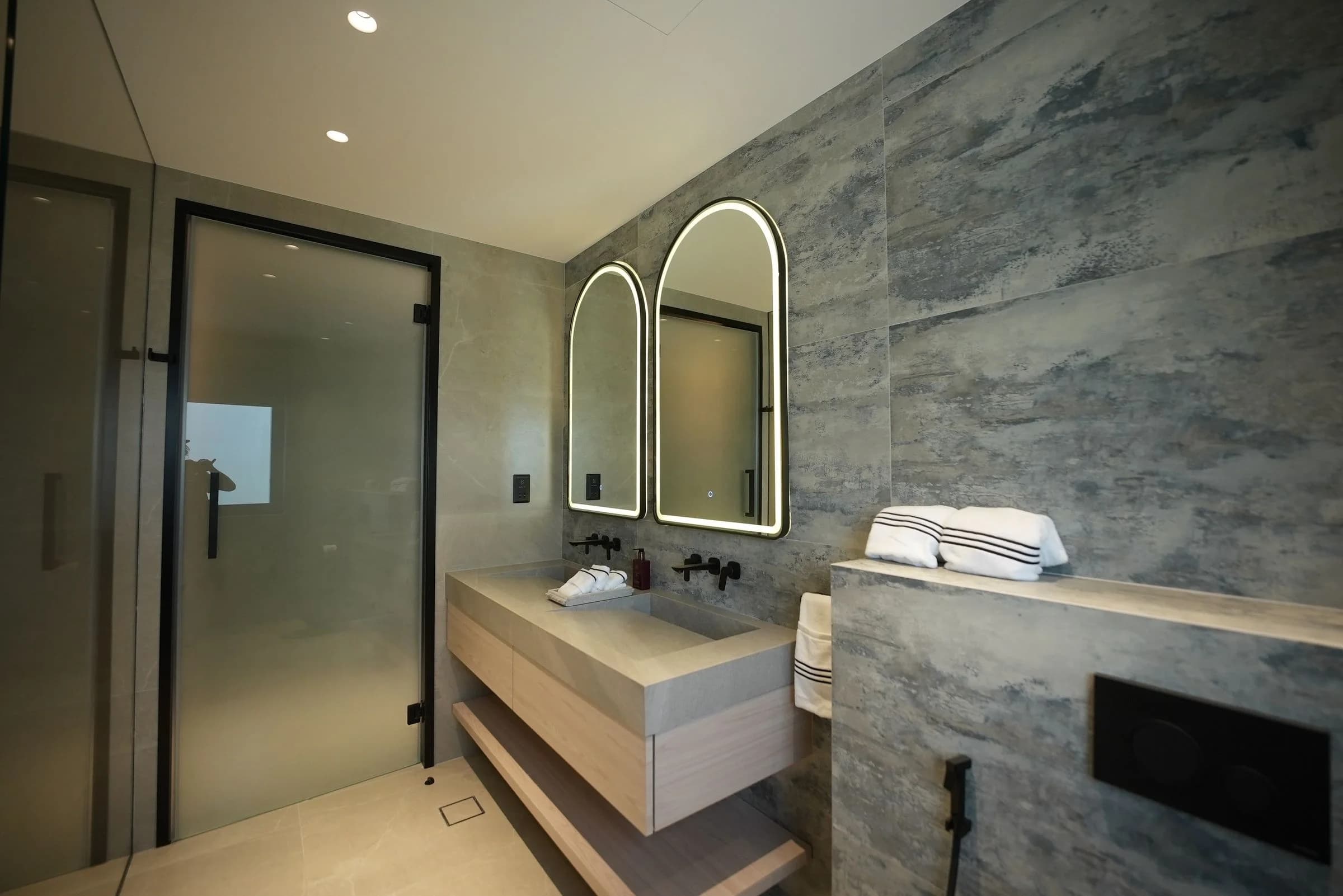 Dubai bathroom with coordinated wall tiles, recessed lighting, glass panels and fitted vanity