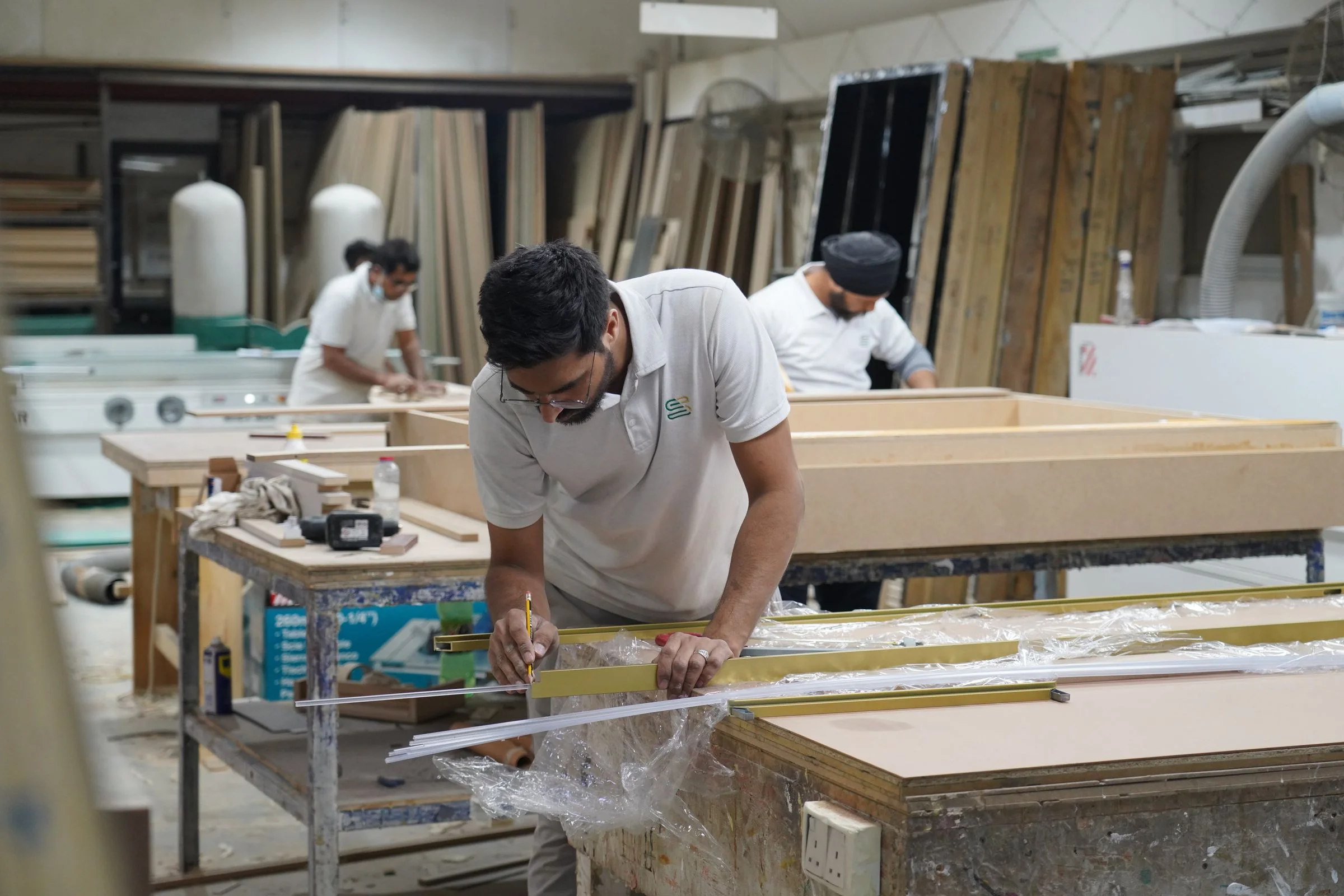Craftsmen measuring and fabricating interior components in a Dubai workshop