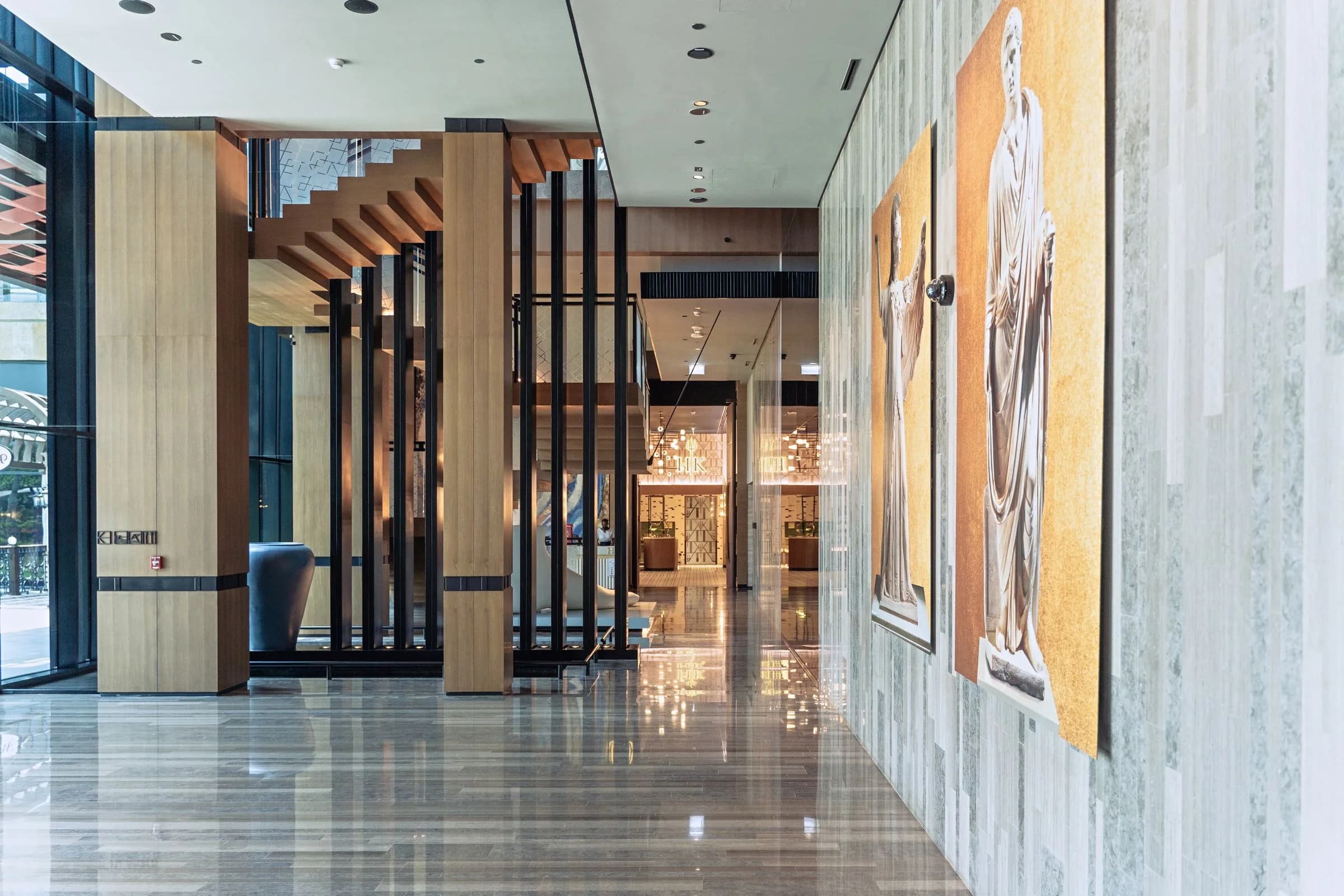 Dubai hotel lobby with timber-clad columns, polished stone flooring, decorative wall finishes and recessed ceiling lighting