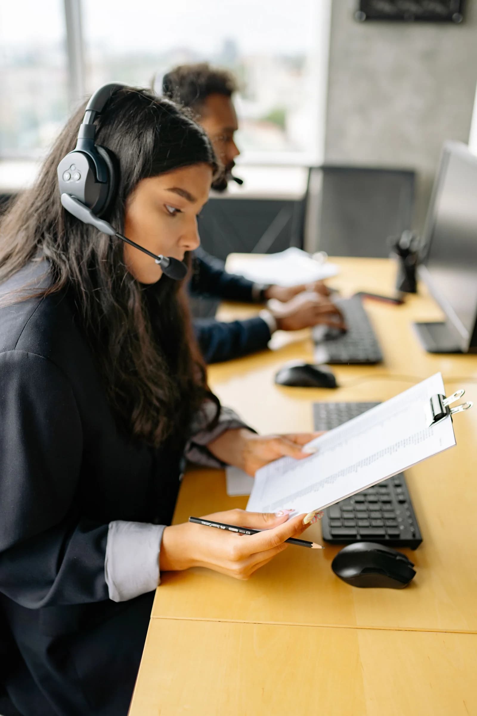 موظفة دعم تراجع المستندات وهي ترتدي سماعة رأس
